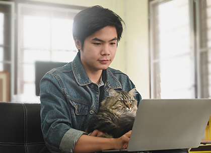 Young man with his cat looking at his laptop